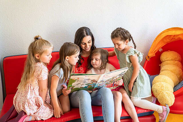 Erzieherin liest Kinder vor.